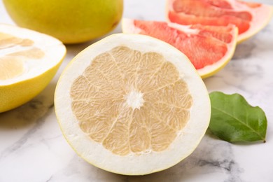 Photo of Different sorts of tasty pomelo fruits on white marble table, closeup