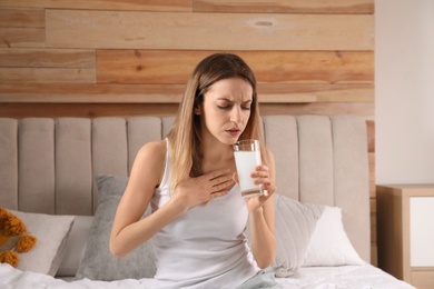 Woman taking medicine for hangover on bed at home