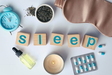 Flat lay composition with word Sleep made of wooden cubes and insomnia remedies on white background