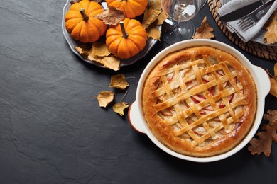Delicious homemade apple pie and autumn decor on black table, flat lay. Space for text