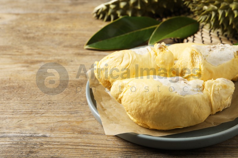Photo of Plate with fresh ripe durian on wooden table. Space for text
