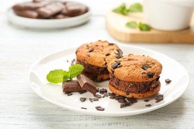 Sweet delicious ice cream cookie sandwiches and chocolate on white wooden table