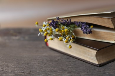 Closed books with beautiful dried flowers on wooden table, closeup. Space for text