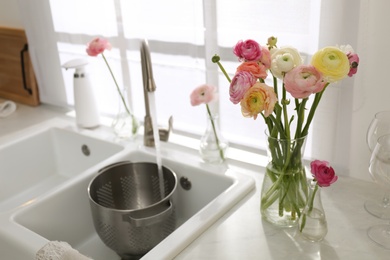 Light kitchen decorated with beautiful fresh ranunculus flowers