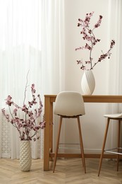 Photo of Beautiful blossoming tree twigs in vases indoors