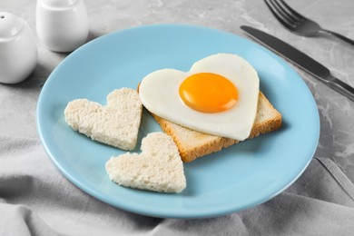 Romantic breakfast with heart shaped fried egg and toasts served on grey marble table