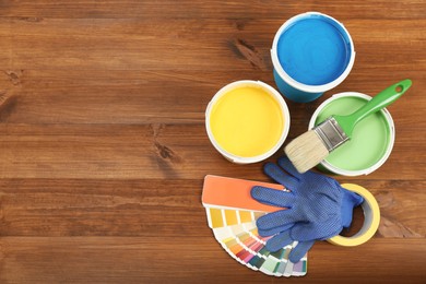 Buckets of paints, palette and decorator's accessories on wooden background, flat lay. Space for text