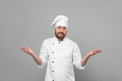 Photo of Puzzled mature male chef on grey background