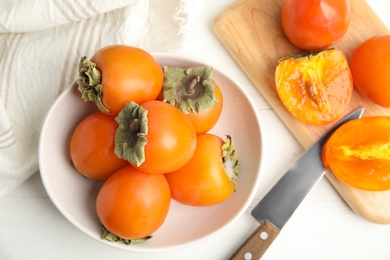 Delicious fresh persimmons on white wooden table, flat lay