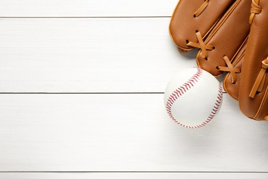 Photo of Catcher's mitt and baseball ball on white wooden table, top view with space for text. Sports game