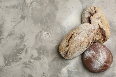 Different kinds of fresh bread on grey table, flat lay. Space for text
