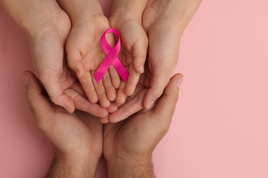 Family holding pink ribbon on color background, top view. Breast cancer awareness