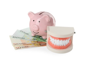 Educational dental typodont model, piggy bank and euro banknotes on white background. Expensive treatment