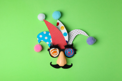 Funny face made of party items on green background, flat lay. April Fool's Day