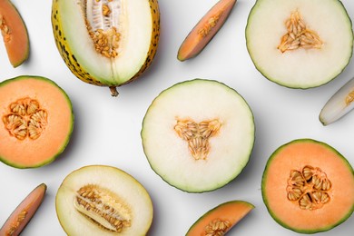 Cut different types of melons on white background, flat lay