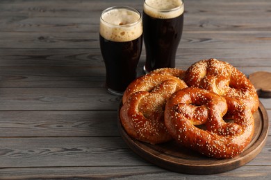 Tasty pretzels and glasses of beer on wooden table, space for text