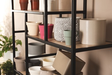 Photo of Shelving unit with many different houseplant pots near beige wall indoors