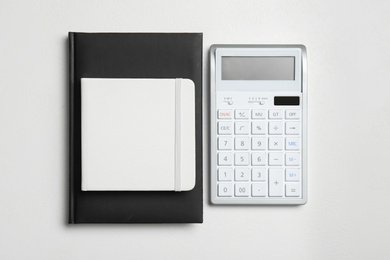 Calculator and notebooks on white background, flat lay. Tax accounting