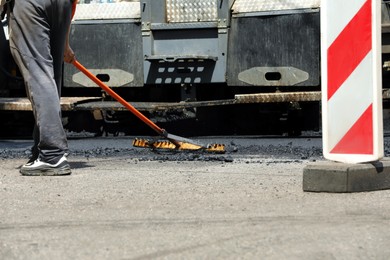 Worker laying new asphalt with paver, closeup. Road repair