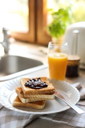 Tasty toasts with jam and glass of juice on countertop in kitchen, closeup. Space for text