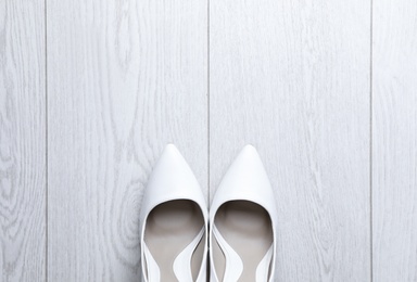 Pair of wedding high heel shoes on white wooden floor, flat lay. Space for text