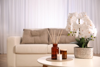 Beautiful orchid and air reed freshener on table indoors. Interior design