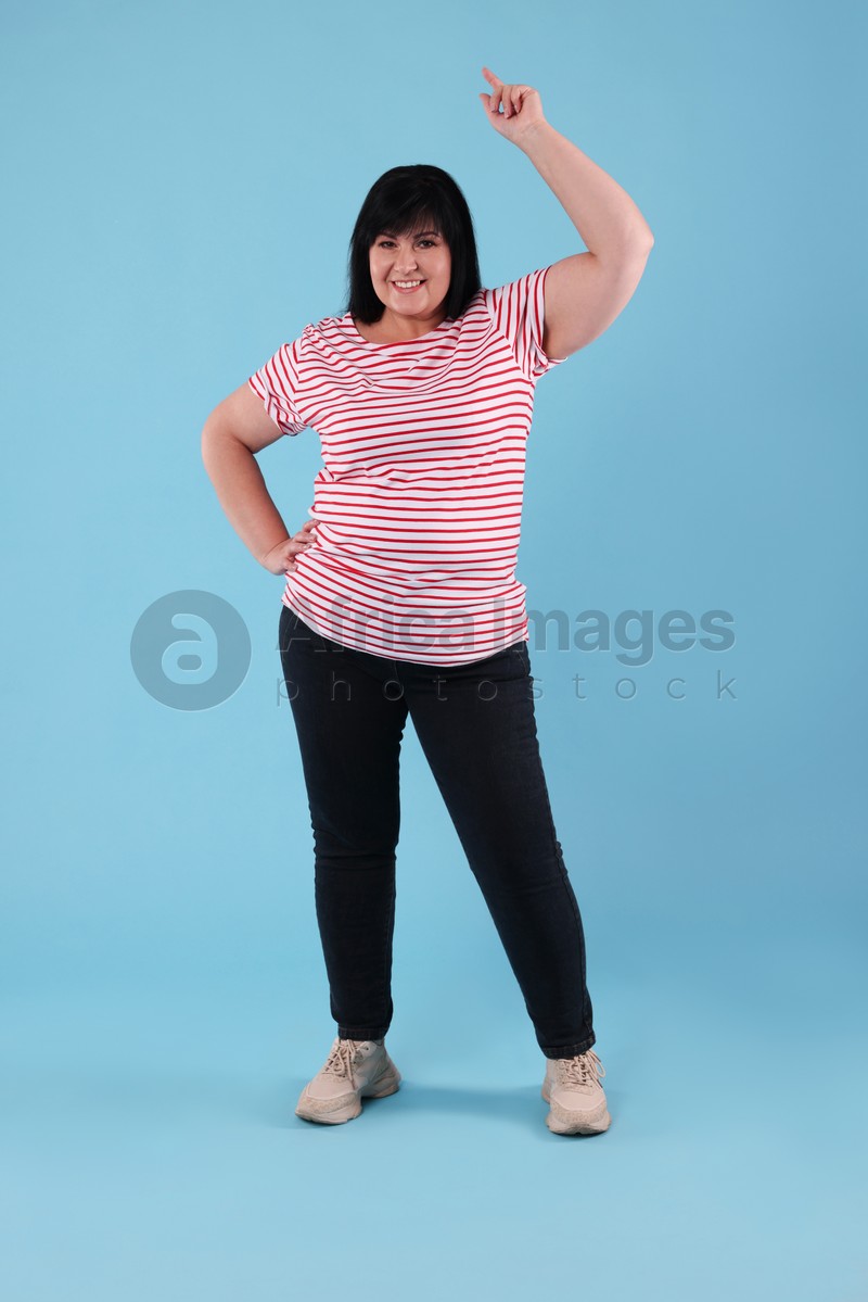 Beautiful overweight mature woman with charming smile on turquoise background 