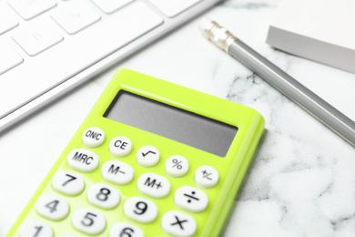 Calculator, keyboard and stationery on white marble table, closeup. Tax accounting
