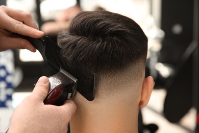 Professional barber making stylish haircut in salon, closeup