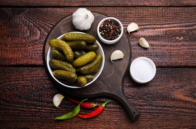 Pickled cucumbers and ingredients on wooden table, flat lay