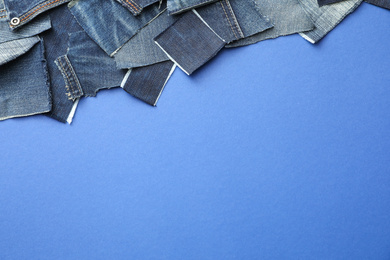 Photo of Flat lay composition with patches of old jeans on blue background. Space for text
