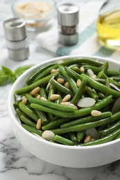 Bowl of tasty salad with green beans on white marble table