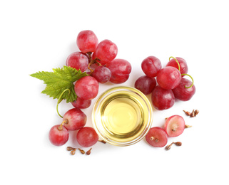 Organic red grapes, seeds and bowl of natural essential oil on white background, flat lay
