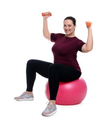 Photo of Happy overweight woman with dumbbells sitting on fitness ball against white background