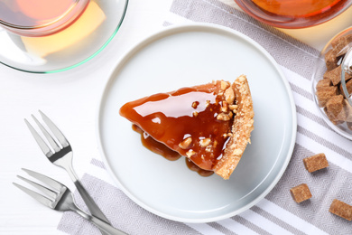 Slice of delicious cake with caramel sauce on table, flat lay