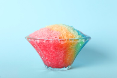 Rainbow shaving ice in glass dessert bowl on light blue background