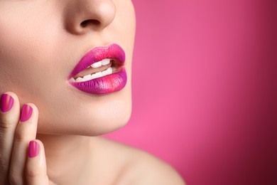 Photo of Young woman with beautiful lips makeup on pink background, closeup. Space for text
