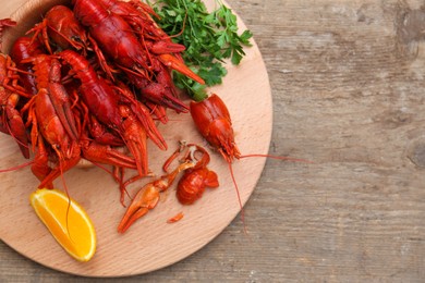 Delicious red boiled crayfish and orange on wooden table, top view