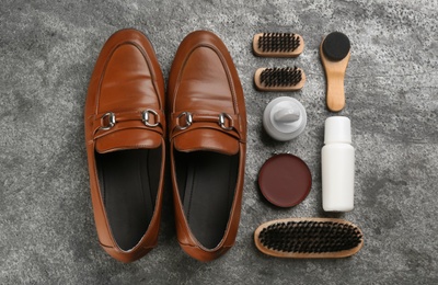 Flat lay composition with shoe care accessories and footwear on grey stone background