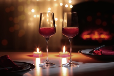 Glasses of wine and candles on table against blurred lights. Romantic dinner