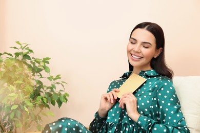 Photo of Happy woman holding greeting card in living room