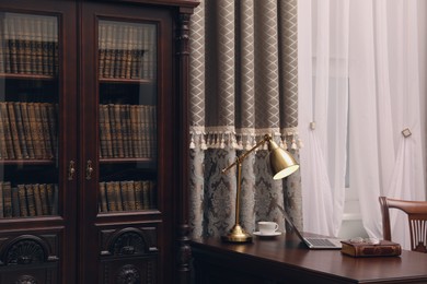 Photo of Library reading room interior with wooden bookcase and table near window