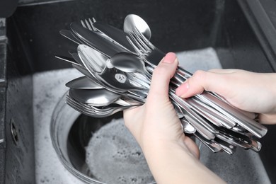 Photo of Woman holding clean silver kitchenware near sink, closeup