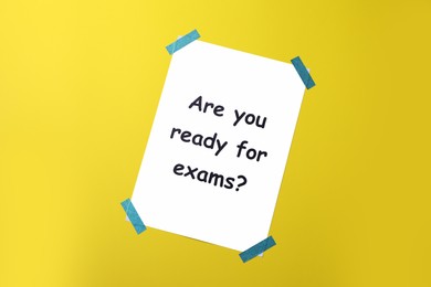 Paper with phrase Are You Ready For Exams on yellow background, top view