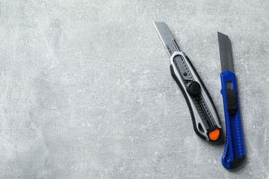 Different utility knives on light grey table, flat lay. Space for text