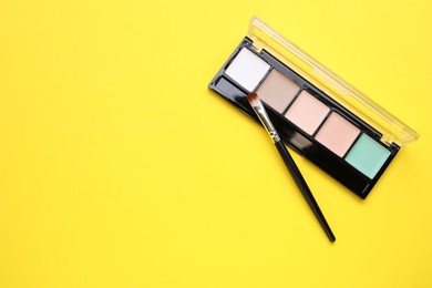 Photo of Colorful contouring palette with brush on yellow background, top view. Space for text