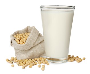 Glass of fresh soy milk and sack with beans on white background