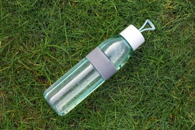 Photo of Bottle of water on green grass, top view. Morning exercise