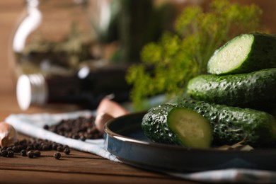 Photo of Fresh cucumbers and other ingredients prepared for canning on wooden table, closeup. Space for text