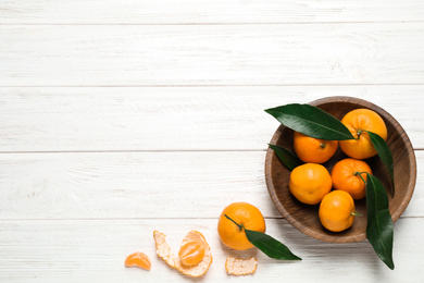 Fresh ripe tangerines with leaves and space for text on white wooden table, flat lay. Citrus fruit